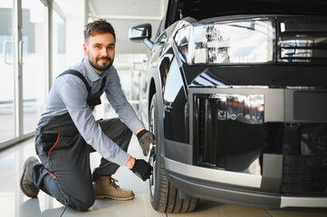 Leinwandbilder - Car mechanic working in garage and changing wheel alloy tire. Repair or maintenance auto service. Replacement of winter and summer tires