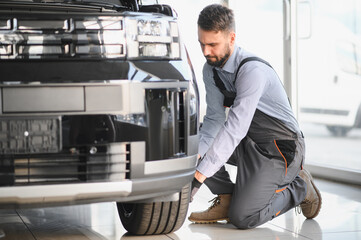 Leinwandbilder - Friendly mechanic in modern car repair shop with car. Professional technician checking vehicle diagnostics and maintenance. Concept of automotive industry and customer service