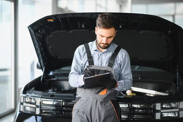 Leinwandbilder - Auto mechanic holding clipboard checklist the car at mechanic shop