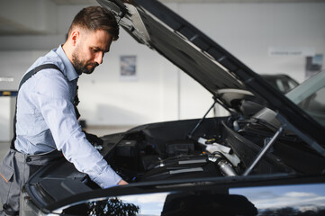 Leinwandbilder - Troubleshooting process. Auto mechanic working in garage. Repair service
