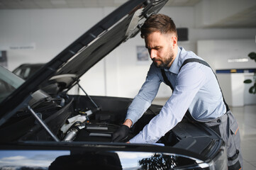 Leinwandbilder - Friendly mechanic in modern car repair shop with car. Professional technician checking vehicle diagnostics and maintenance. Concept of automotive industry and customer service