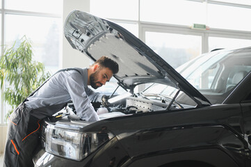 Leinwandbilder - Friendly mechanic in modern car repair shop with car. Professional technician checking vehicle diagnostics and maintenance. Concept of automotive industry and customer service