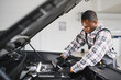 © Serhii - portrait of positive afro american auto mechanic in uniform, he is keen on repairing cars, automobiles