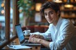 © Robbie Smith 1  - Young man working on laptop, boy freelancer or student with computer in cafe at table looking in camera.