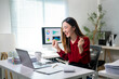 © Apichat - A woman is sitting at a desk with a laptop and a cup of coffee