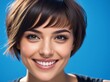 © moonart - Bright smile of a young woman with short hair against a blue background radiates happiness and confidence in a studio setting
