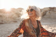 © lashkhidzetim - woman with a big smile on her face is wearing sunglasses and a colorful outfit. She is standing on a sandy beach, enjoying the sun and the beautiful surroundings