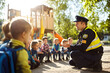 © Iriyalo - A police officer teaches children about safety and civil defense outdoors on a sunny day at a playground