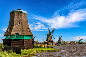 Wall Mural - Dutch typical landscape. Traditional old dutch windmills against blue cloudy sky in the Zaanse Schans village