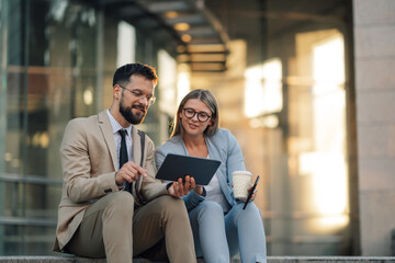 Business people working on tablet and having informal meeting outside office