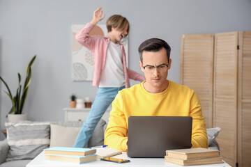 Canvas Print - Working young man stressed of his noisy little son at home