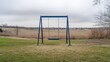 © MohamadIzzudin - Empty Swing Set in a Quiet Park Surrounded by Open Fields and Overcast Skies, Evoking a Sense of Tranquility and Nostalgia in Nature’s Embrace