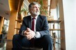 © opolja - Business portrait - mature businessman sitting in office lobby. Male executive relaxing in office lounge