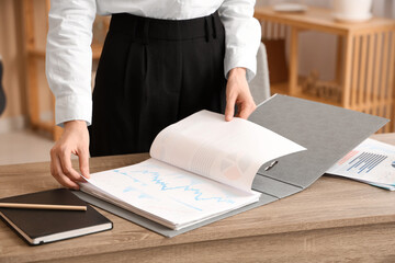 Sticker - Young businesswoman looking through folder with documents in office. Closeup