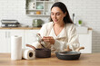 © Pixel-Shot - Beautiful young happy woman wiping pots with paper towels in kitchen