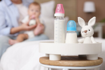 Canvas Print - Tray with baby bottles of milk and toy bunny on table in bedroom, closeup