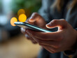 © webdesign - Person holding a smartphone in an urban night setting with blurred background lights.