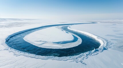 Wall Mural - Aerial view of a winding river flowing through a frozen landscape under a clear blue sky