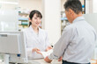 © buritora - 薬局で薬の相談を受ける高齢者男性と薬剤師・調剤師の女性
