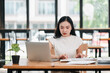 © Satori Studio - Young woman concentrating on her laptop in a bright, modern office setting with large windows and greenery outside.