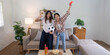 © Natee Meepian - LGBT couple celebrating a soccer match at home, posing joyfully with snacks and excitement