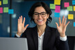 © Andres Mejia - Smiling businesswoman waving during video conference in office
