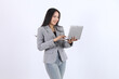 © Miftakhul Fariz - Beautiful woman in gray suit and jeans is typing on laptop. Business asian woman