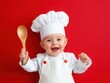 © Khritthithat - Adorable baby chef wearing a white outfit and chef hat holding wooden spoon, smiling joyfully against vibrant red backdrop, celebrating culinary creativity