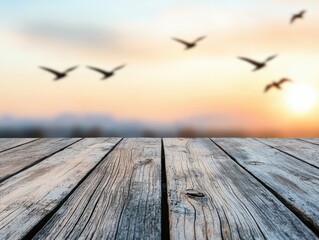 Wall Mural - Empty wooden table with blurred mountain background and flying birds at sunset