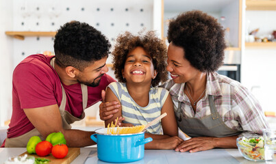 Wall Mural - overjoyed young african american family with kid have fun cooking at home together,