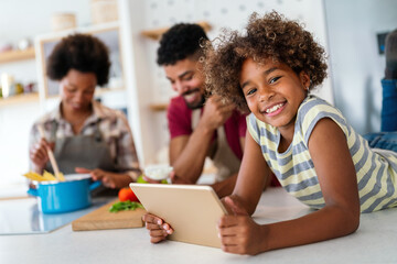 Wall Mural - happy smiling african american parents enjoy weekend play with child in kitchen. family love concept