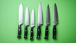© gan - Six kitchen knives of various sizes and types laid out against a green background