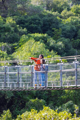 Wall Mural - Family backpacking. Mother and son standing on suspension bridge looking at the sights.