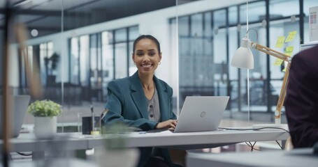 Aufkleber - Portrait of a Beautiful African Manager Working on Laptop Computer in a Modern Office with Glass Walls. Young Black Female Posing Behind Her Desk, Looking at Camera and Smiling