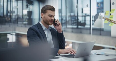 Aufkleber - Young Entrepreneur Negotiating a Deal on Phone while Checking Emails on Laptop Computer. Confident and Professional Man Communicates with Clients while Sitting Behind a Desk in Office