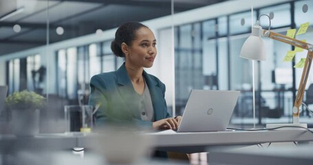 Aufkleber - Young Black Businesswoman Leads an Online Team Meeting on Laptop Computer while in Office. She Provides Project Updates, Browses Data on Internet and Brainstorms Solutions with a Colleagues