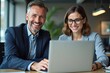 © Fazla - Happy Professional Business Man and Woman Working on a Laptop at an Office Meeting, Two Busy Colleagues Collaborating and Discussing a Business Plan Together. Generative AI