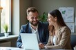 © Fazla - Happy Professional Business Man and Woman Working on a Laptop at an Office Meeting, Two Busy Colleagues Collaborating and Discussing a Business Plan Together. Generative AI