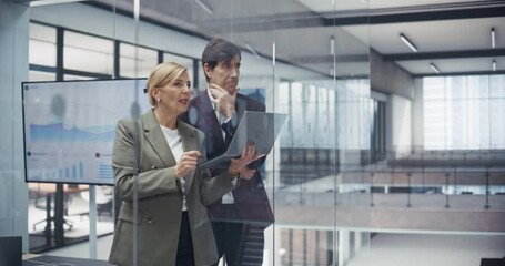 Aufkleber - Two Middle Aged Managers Discussing Project Challenges In Modern Office, Standing Behind a Glass Wall with a Laptop Computer, Having a Conversation About Management, Marketing, Budget and Strategy