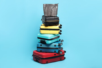 Wall Mural - Stack of colorful suitcases and bag on light blue background