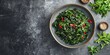 © Ahmad - Wakame seaweed salad garnished with sesame seeds and red chili peppers arranged in a gray bowl on a textured dark surface with ample copy space
