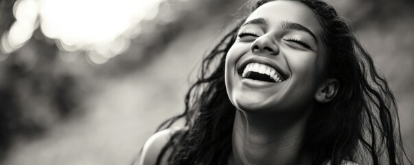 Wall Mural - Joyful young woman with long hair laughing playfully, showing carefree spirit. Black and white portrait highlighting emotions and movement.