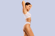 © Prostock-studio - Bodycare Concept. Profile Side View Portrait Of Slim Woman With Perfect Ideal Body Shape Posing With Raised Arms Isolated On Blue Studio Background, Wearing White Top And Panties, Free Copy Space