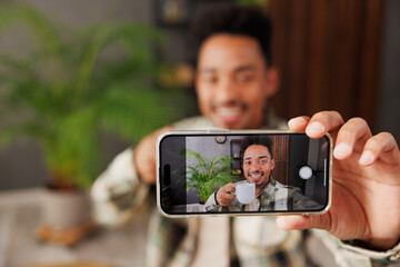 Canvas Print - Young man he wear grey casual clothes doing selfie shot on mobile cell phone post photo on social network sitting alone at table in coffee shop cafe relax rest in restaurant during free time indoors.