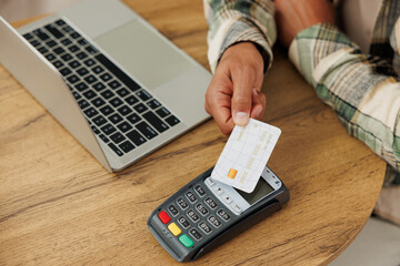 Sticker - Cropped young IT man wear casual clothes hold wireless modern bank payment terminal process acquire credit card sitting at table in coffee shop cafe relax rest in restaurant during free time indoors.