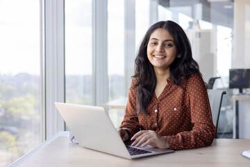 portrait young successful woman at her workplace inside the office. businesswoman smiling and lookin