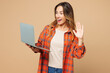 © ViDi Studio - Young shocked surprised IT woman wear orange shirt casual clothes hold use work on laptop pc computer waving hand talk speak isolated on plain pastel light beige background studio. Lifestyle concept.