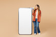 © ViDi Studio - Full body young woman wear orange shirt casual clothes big huge blank screen mobile cell phone smartphone with workspace copy space mockup area scream in megaphone isolated on plain beige background.