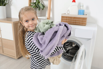 Wall Mural - Little helper. Cute girl doing laundry at home