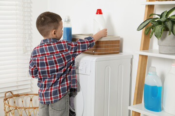 Wall Mural - Little helper. Cute boy doing laundry at home